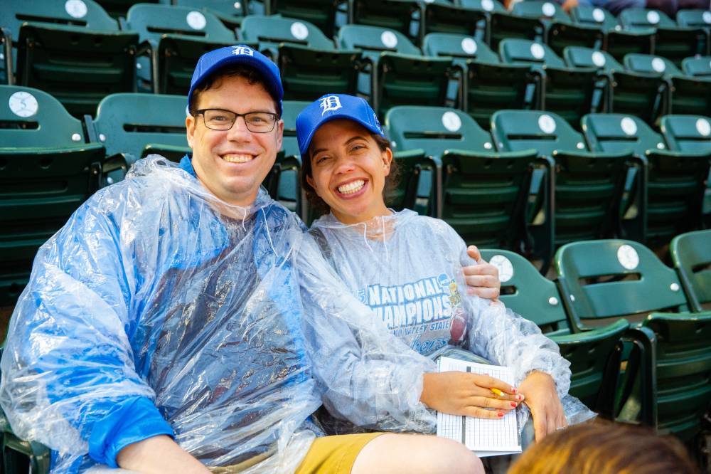 A couple smiling and wearing a poncho at the Comerica Park event